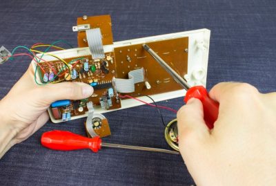 Engineer repairs chip board with red screwdriver