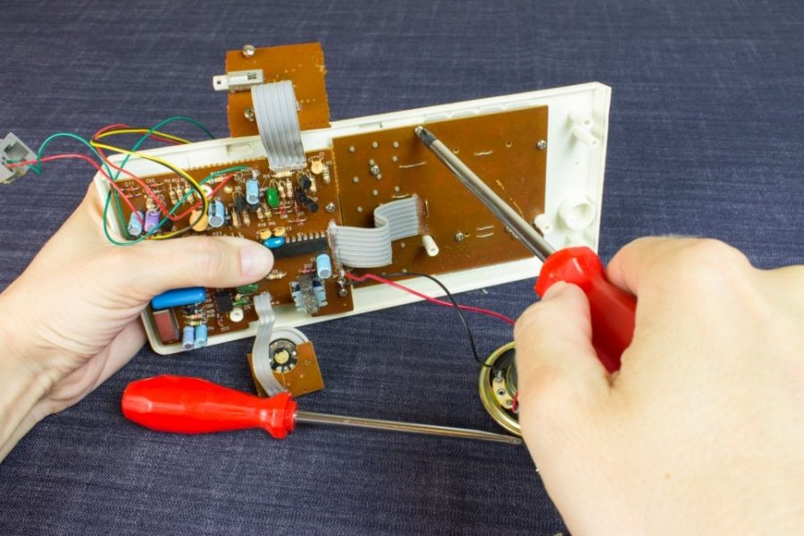 Engineer repairs chip board with red screwdriver