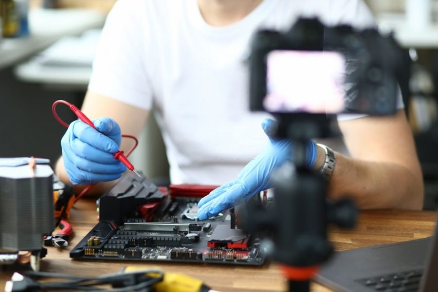 Close-up view of person measuring voltage using voltmeter and filming it on videocamera. Male recording video for vlog. Beginner vlogger or hobby for repairman concept