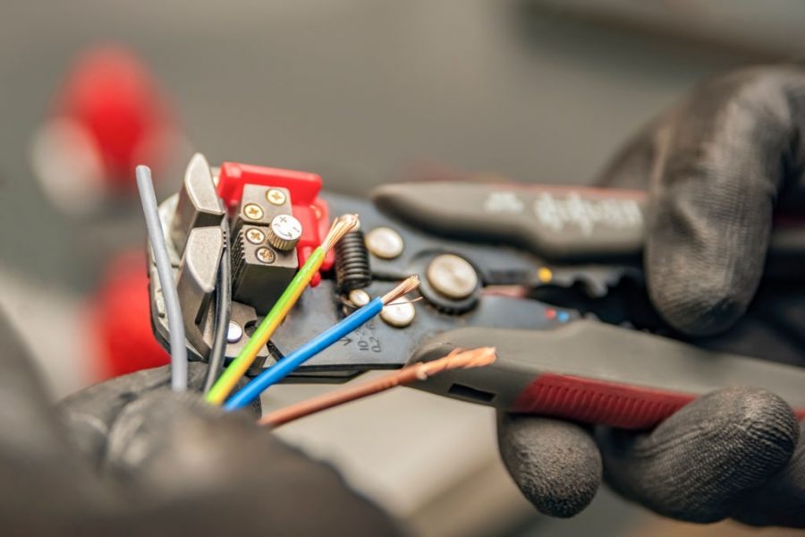 Wire strippers. The electrician cleans the protective insulation from the wire using a wire stripper. The process of connecting wires. close-up.