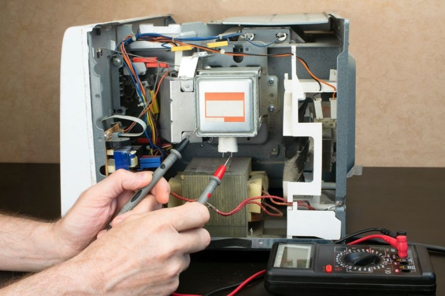 Repair of a microwave oven, repair of household appliances. The master measures the voltage with a tester