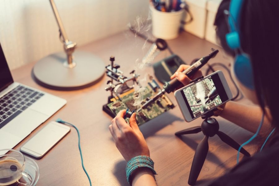 Young woman soldering computer parts at home